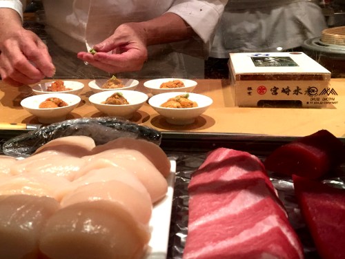 Sushi chef at work plating dish after dish of uni for non-sushi bar patrons.